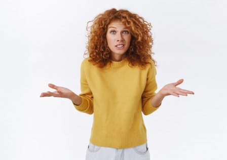 Girl apologizing, shrugging as dont know, cant help. Cute silly and awkward redhead woman in yellow sweater, spread arms sideways, smiling clumsy and embarrassed, admit her fault, white background.